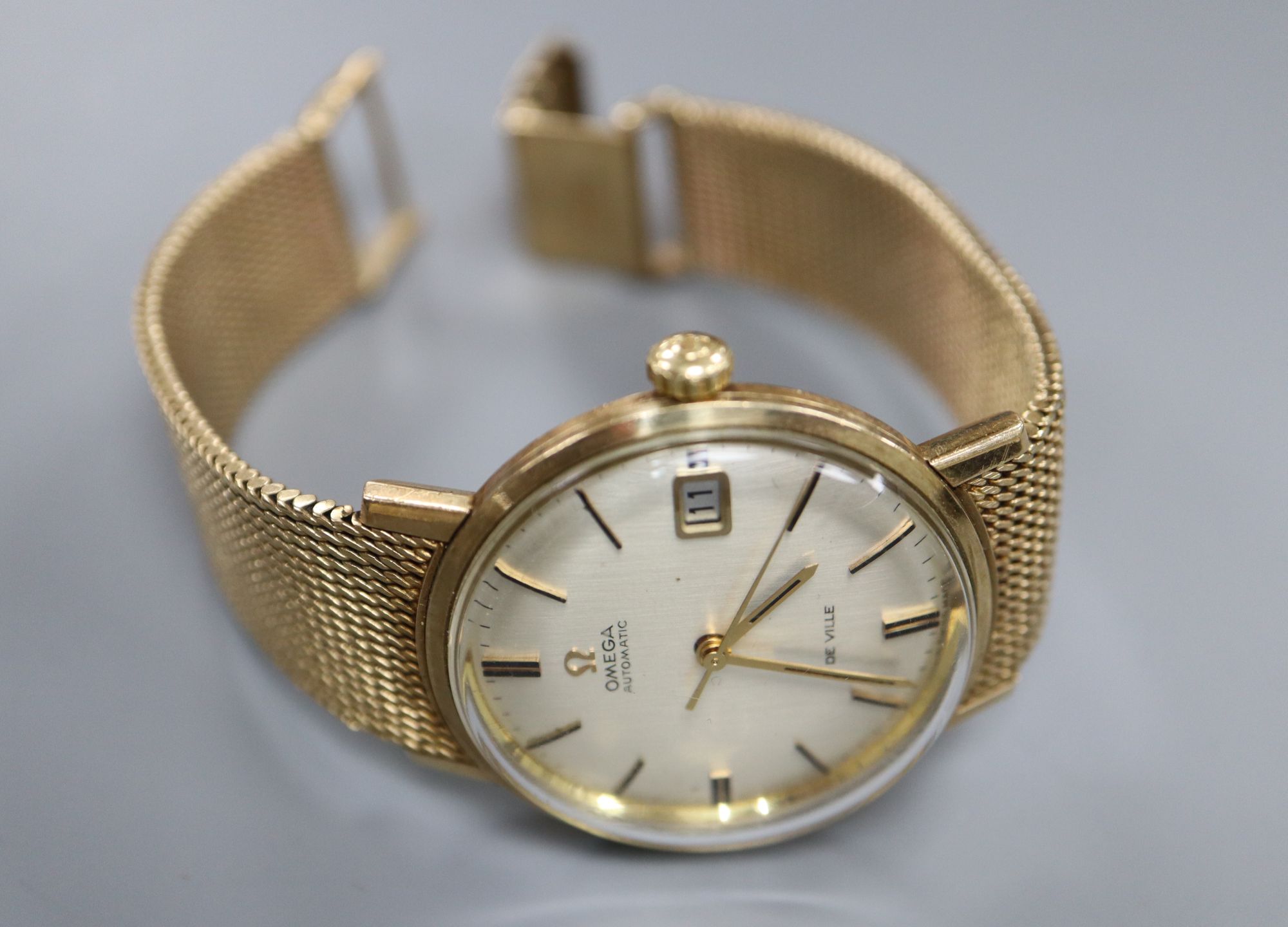 A gentlemans early 1970s 9ct gold Omega De Ville automatic wrist watch, on integral Omega 9ct gold bracelet,